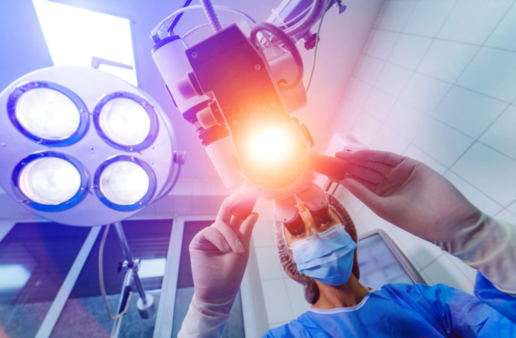A close-up of an eye surgeon looking under the surgical scope in an operating room while performing laser surgery on a patient with high myopia.
