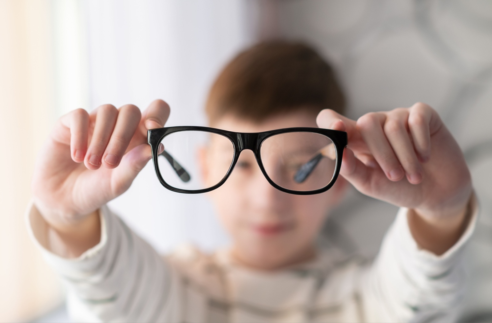 A child holds up the corrective lenses used to help treat their myopia symptoms.