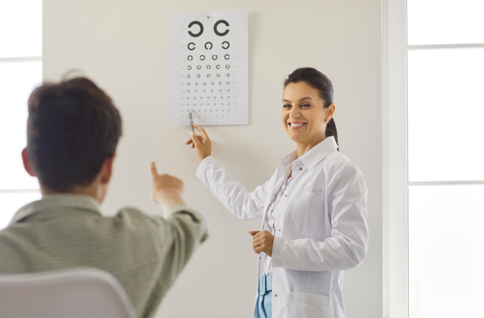 An eye care practitioner performs a vision test to monitor the progression of their patient's myopia.