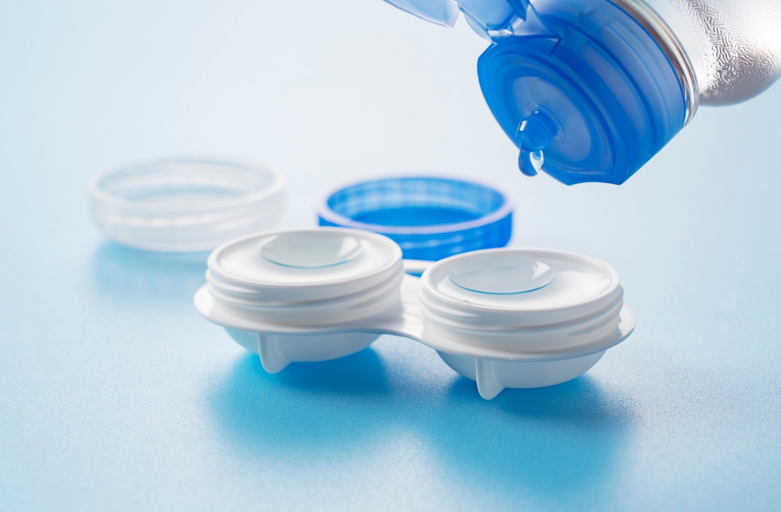 An image of a contact lens solution being poured into a contact lens case.