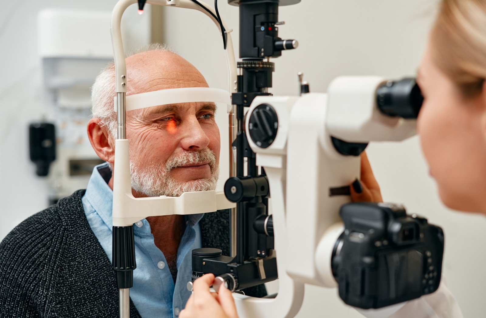 An optometrist carefully examining an older adult's eyes during a routine comprehensive eye exam.