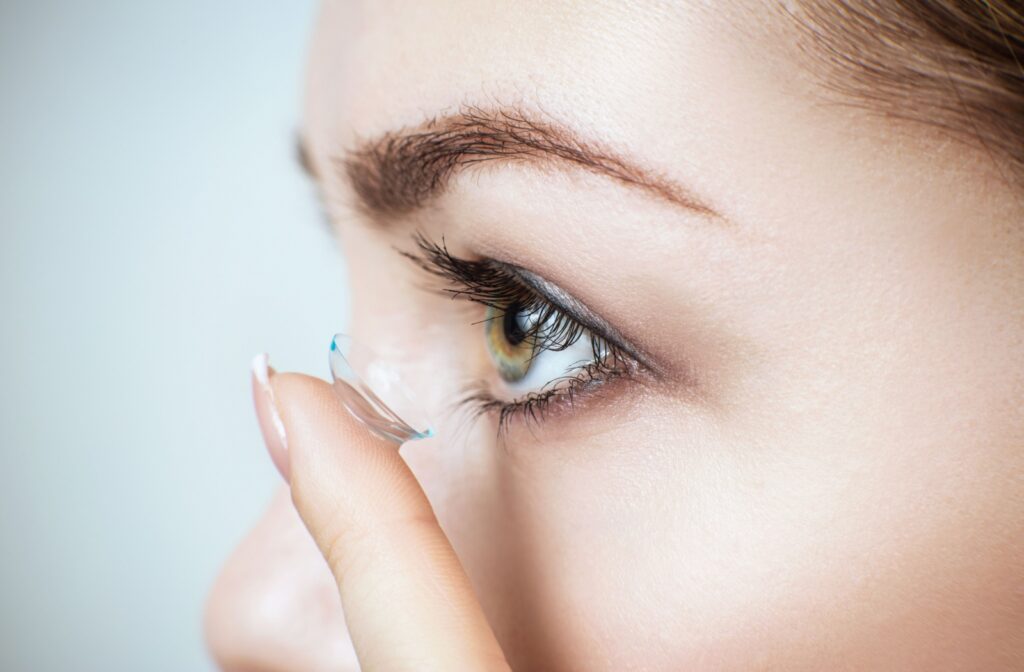 Close-up of a woman inserting a disposable contact lens into her eye.