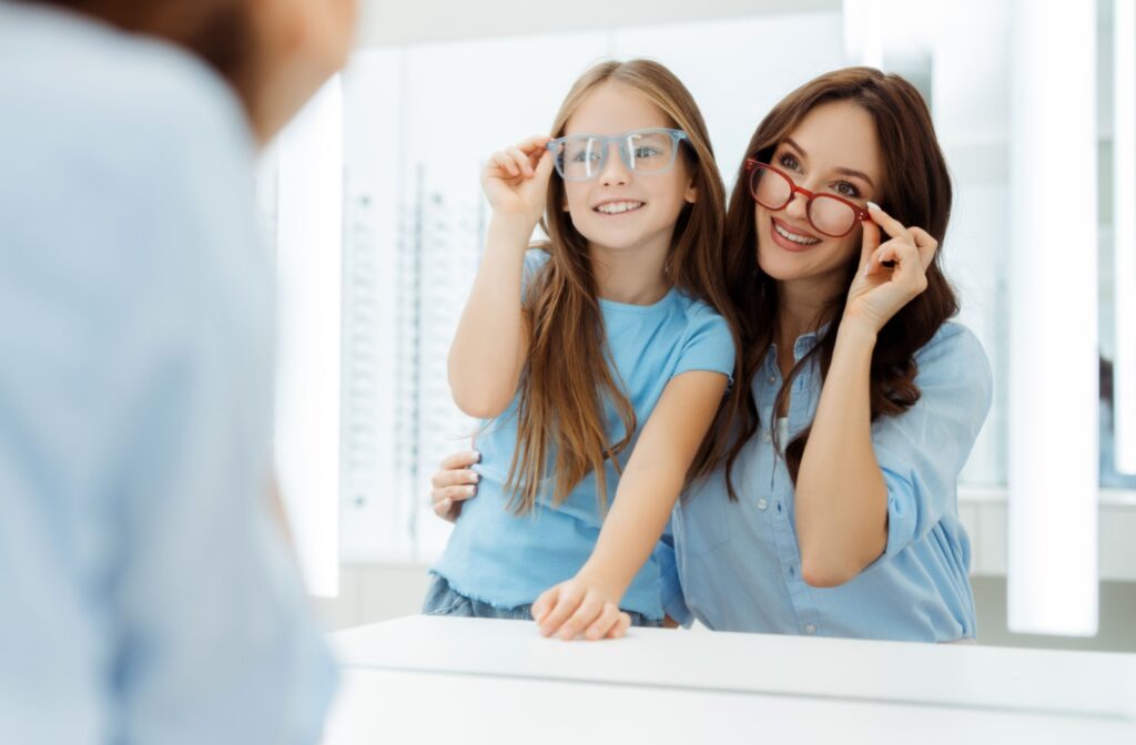 Mother and daughter trying on eyeglasses together at an optometrist's office.