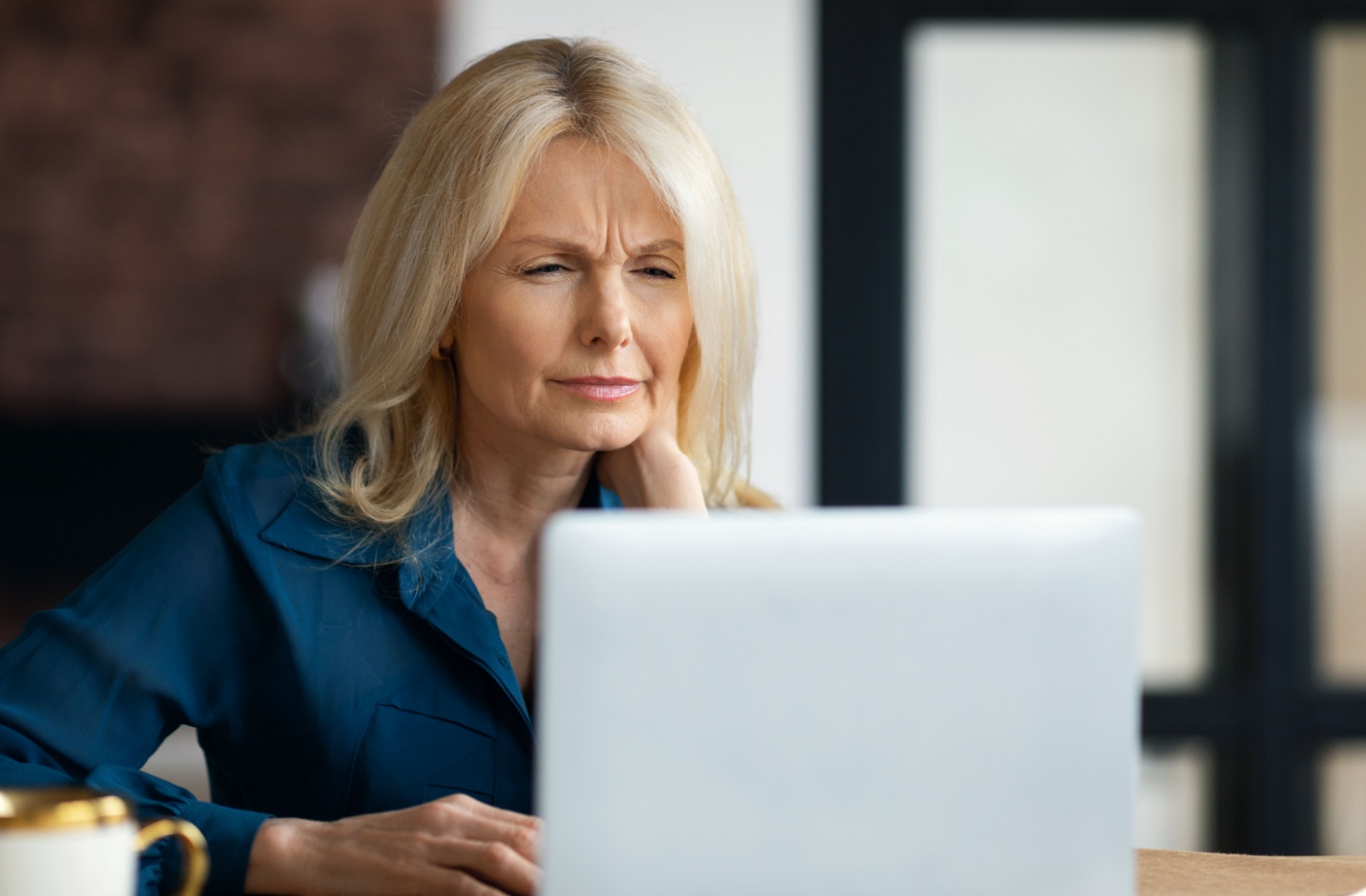 An older adult squints because they can't quite see clearly while working on their computer.