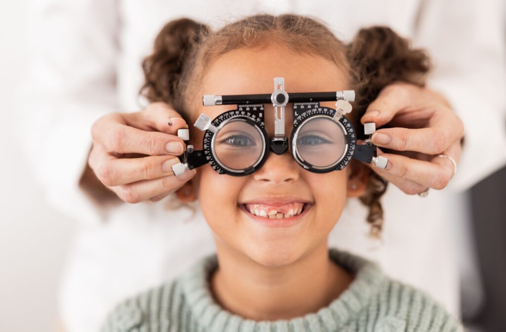 A child smiles while wearing a trial lens frame during a children’s eye exam.