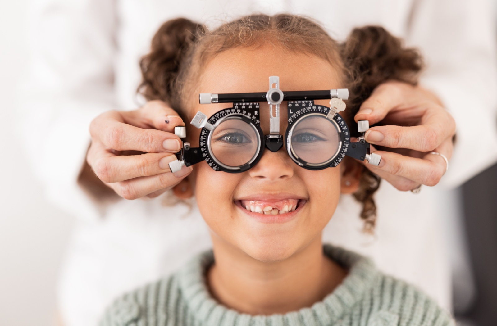 A child smiles while wearing a trial lens frame during a children’s eye exam.