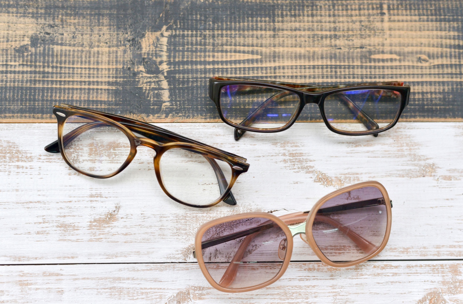 Three pairs of eyewear on top of a wooden background
