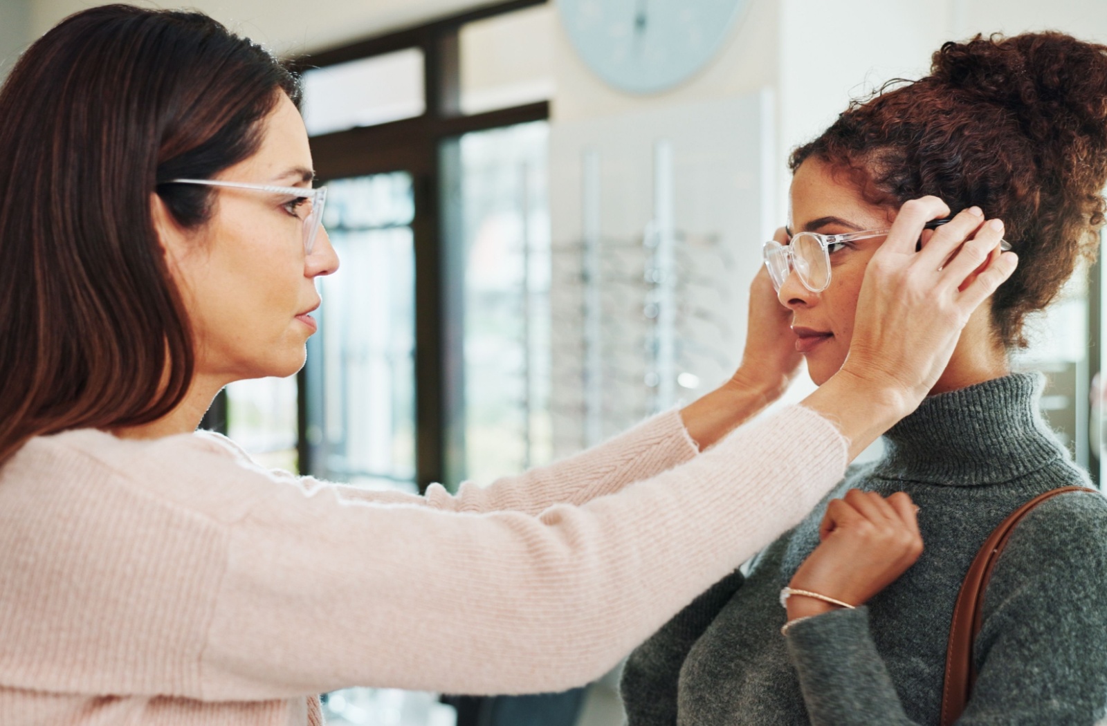 An optician helps a customer get their glasses fitted properly to their face